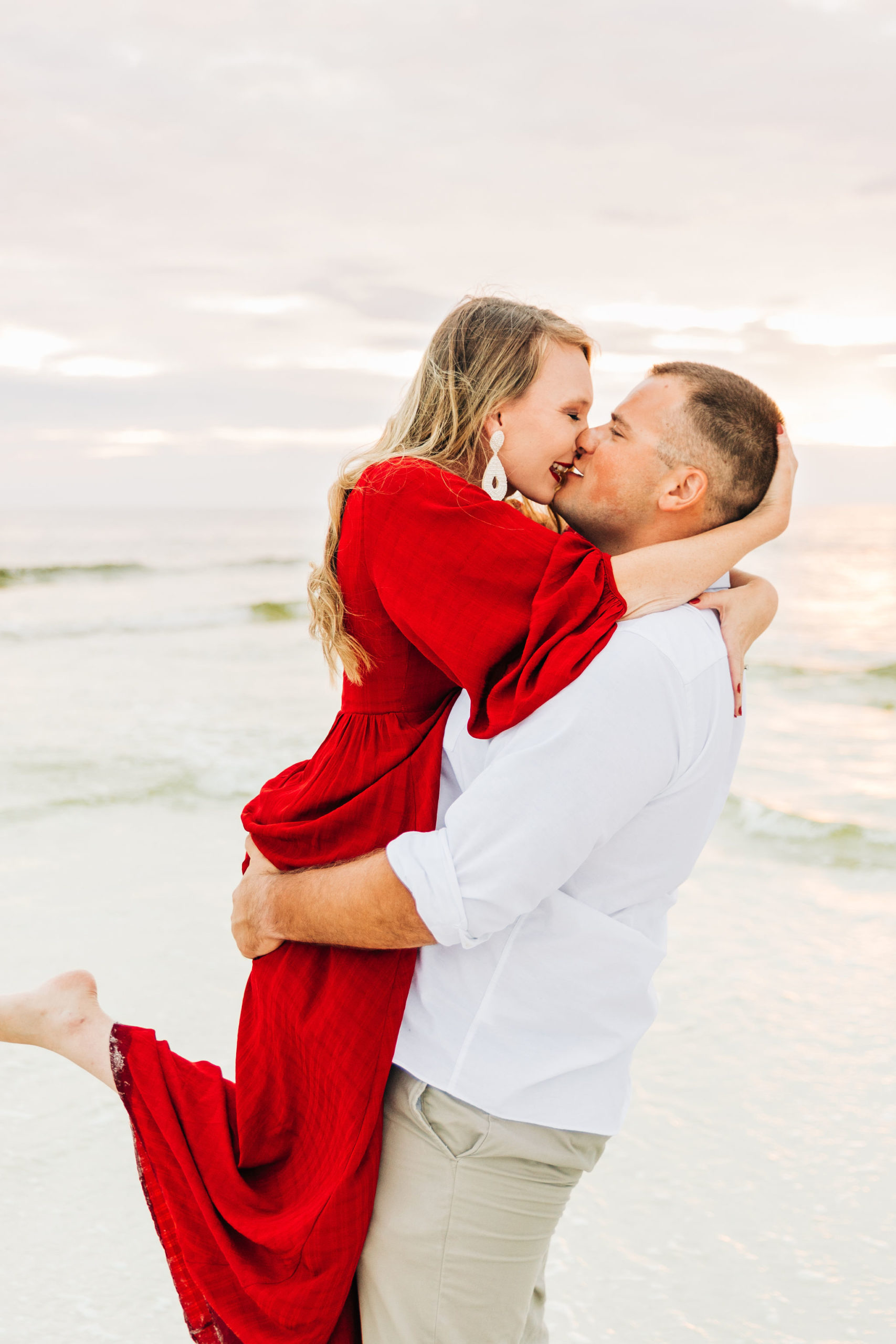 Noah picks Kallie up for a kiss as the waves splash behind them