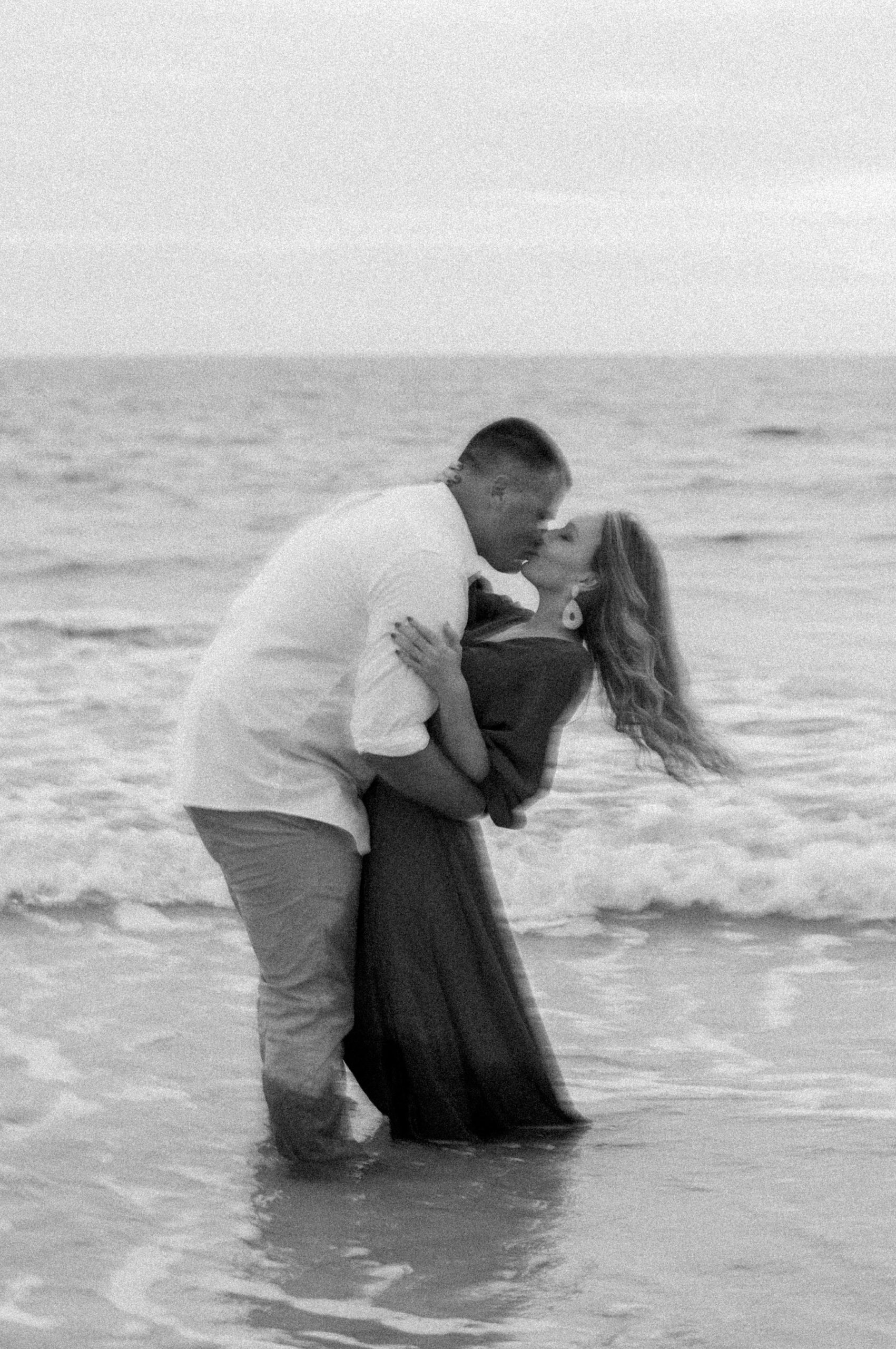 Kallie and Noah kiss as they dip they feet in the water at the Destin beach