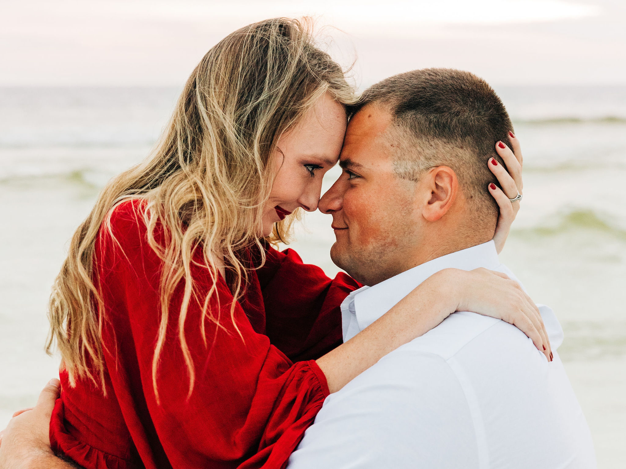 Kallie pulls Noah in close and they touch foreheads as she sits on his lap in the sand