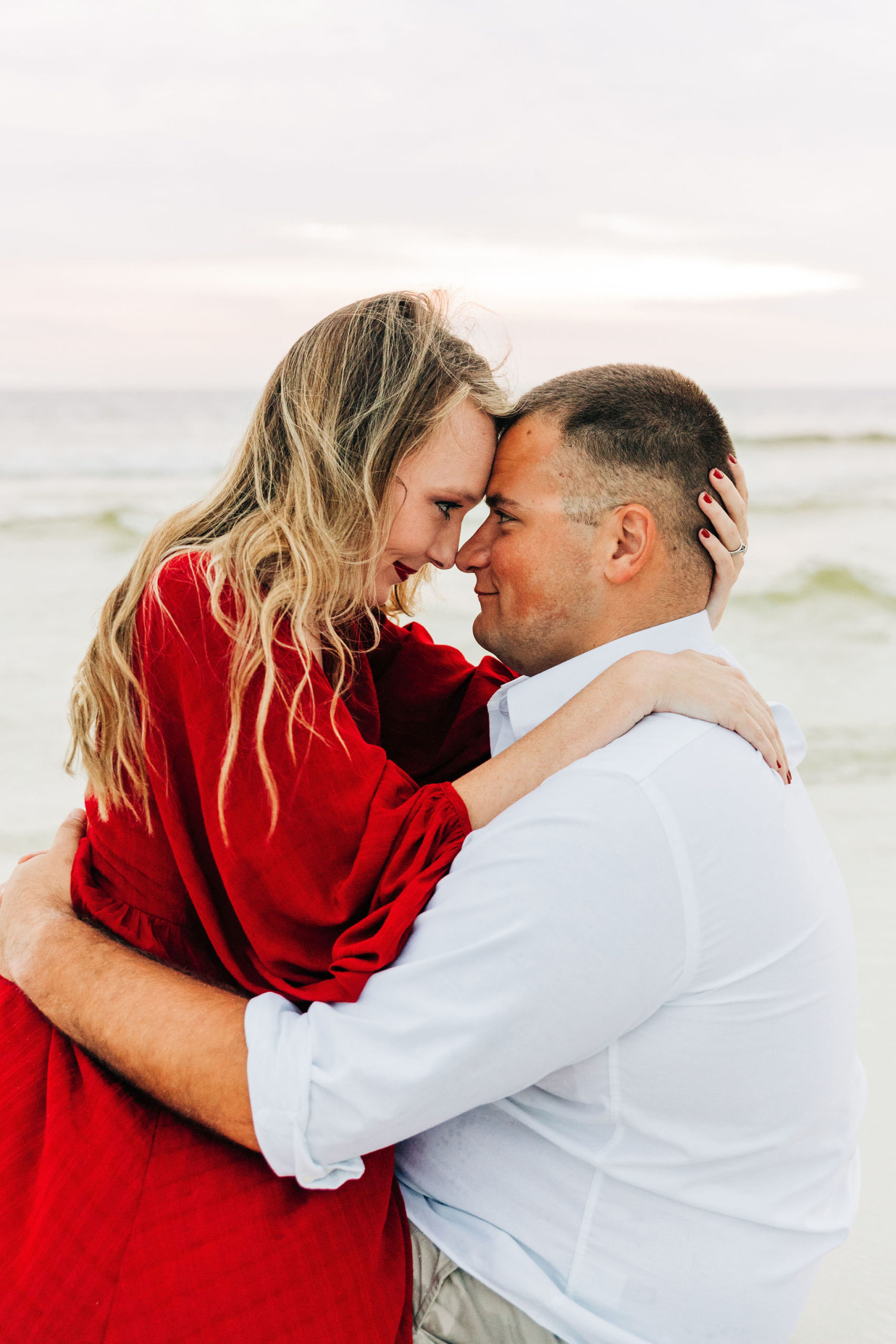 Kallie pulls Noah in close and they touch foreheads as she sits on his lap in the sand